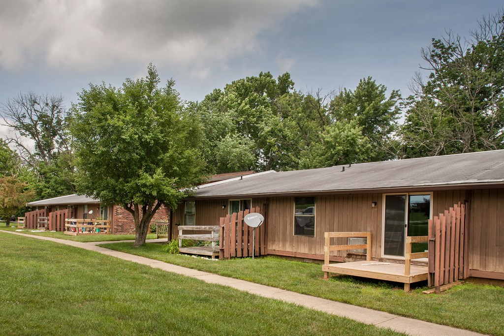 a wooden building with a porch and a yard with trees