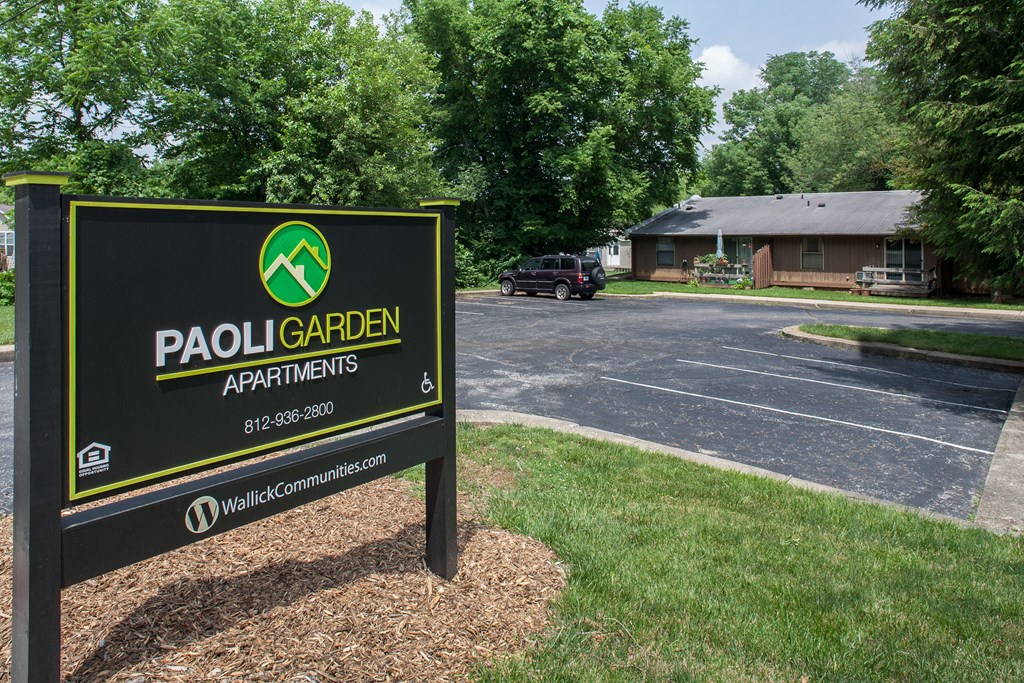 a sign for pablo garden apartments in front of a parking lot