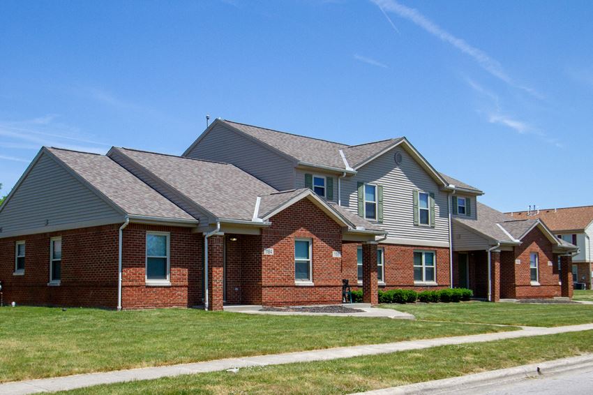 a brick house with a gray roof and a sidewalk