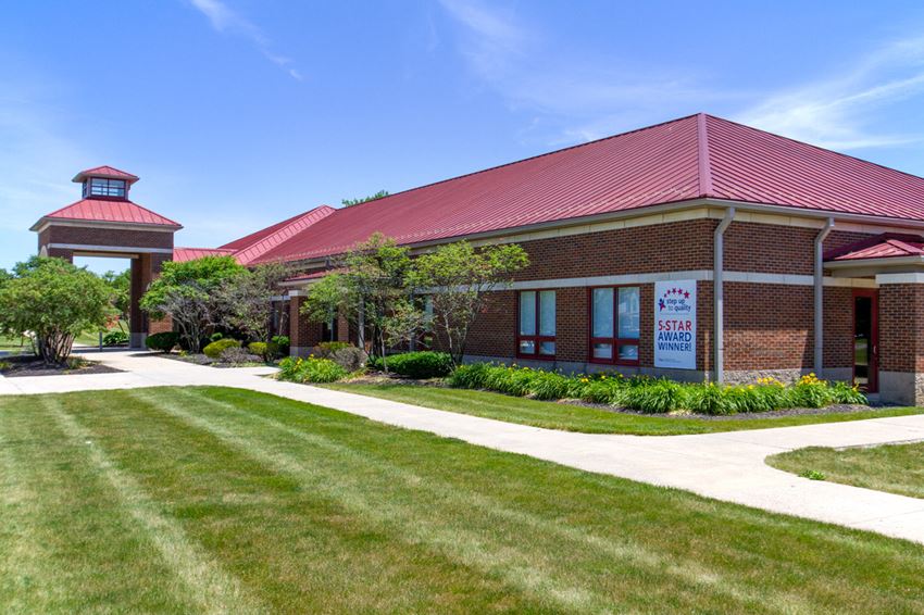 the front of a brick building with a lawn and walkway