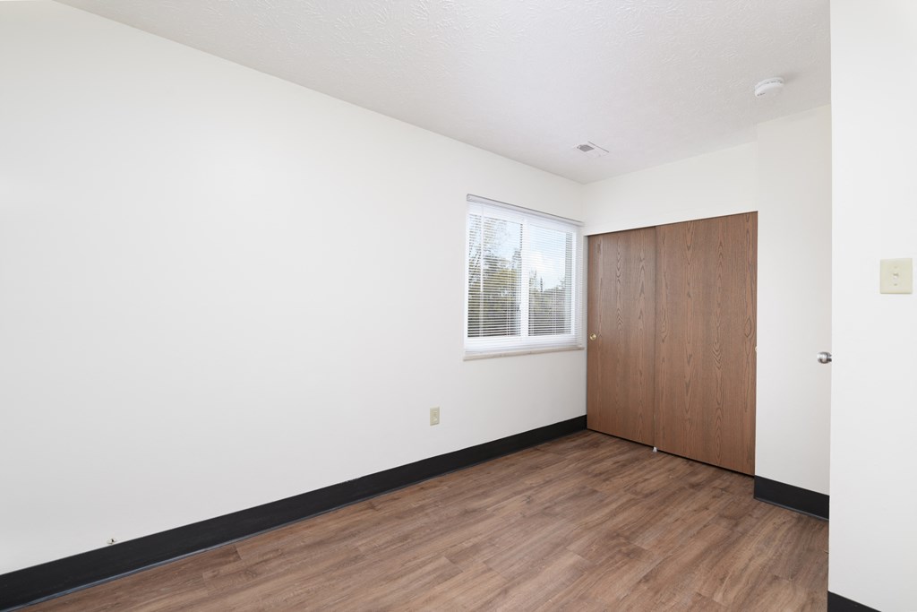 an empty room with white walls and wood flooring and a wooden door and window