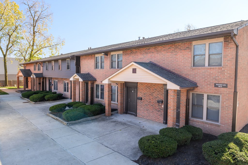 a sidewalk in front of a brick apartment building