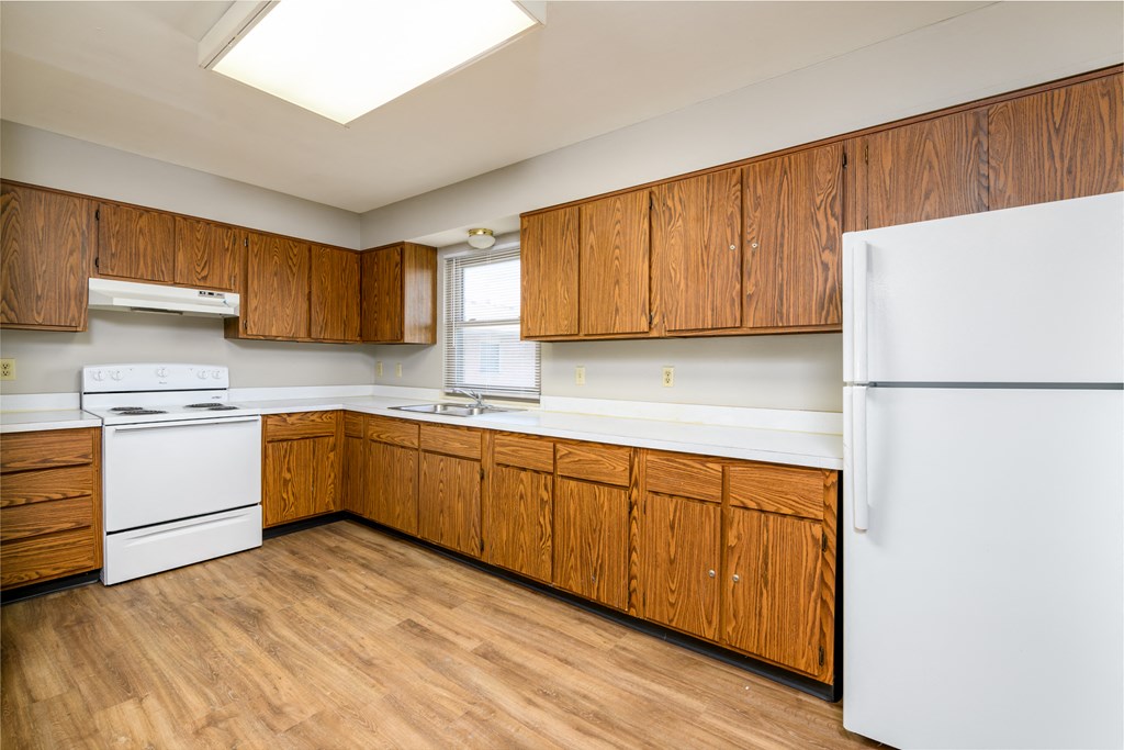 an empty kitchen with white appliances and wooden cabinets