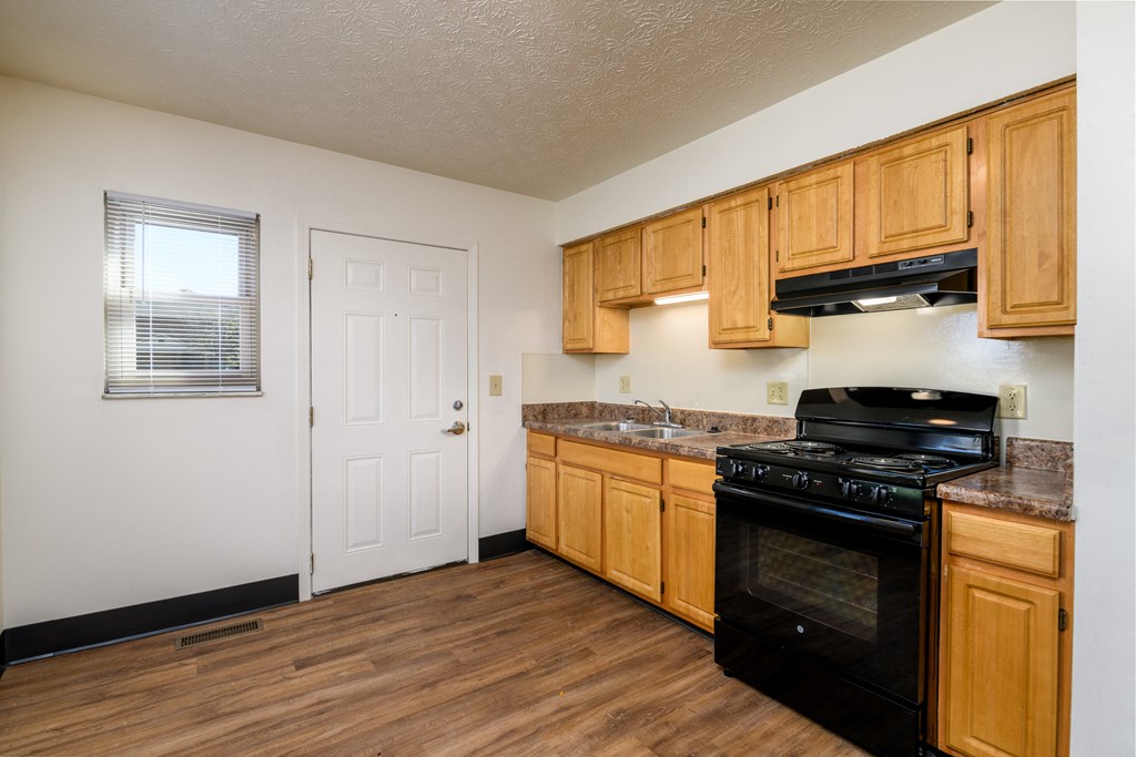 an empty kitchen with wooden cabinets and black appliances