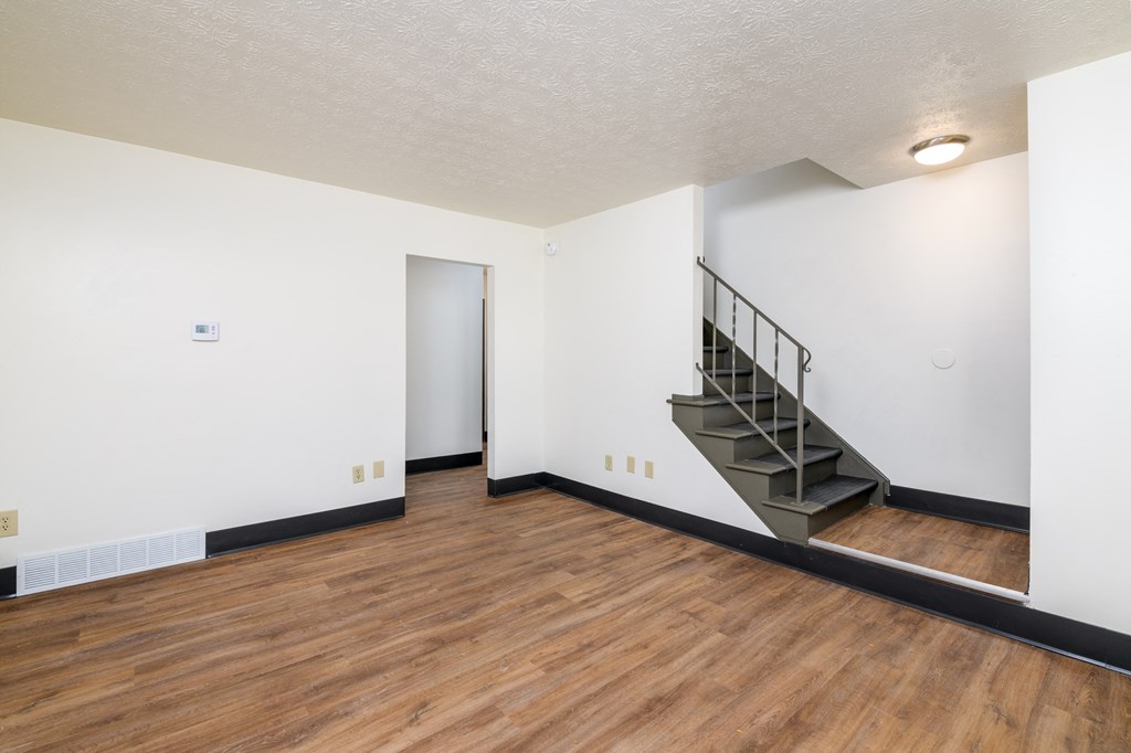 an empty living room with wood flooring and a staircase