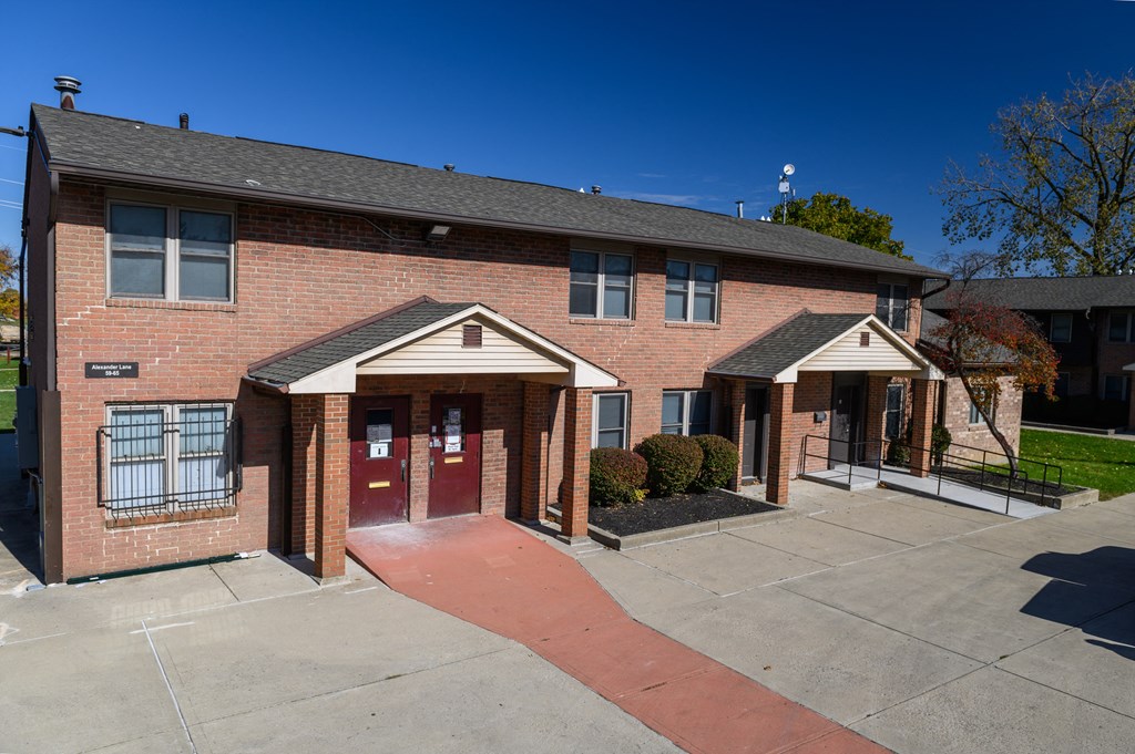 a brick apartment building with a walkway in front of the front door