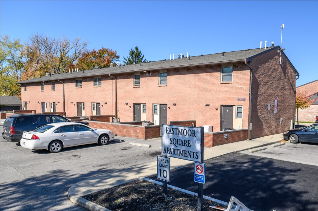 a brick building with a sign in front of a parking lot