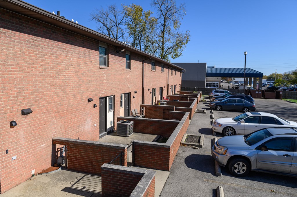 the side of a brick building with cars parked in a parking lot