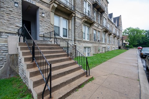 a set of stairs in front of a stone building with black railings