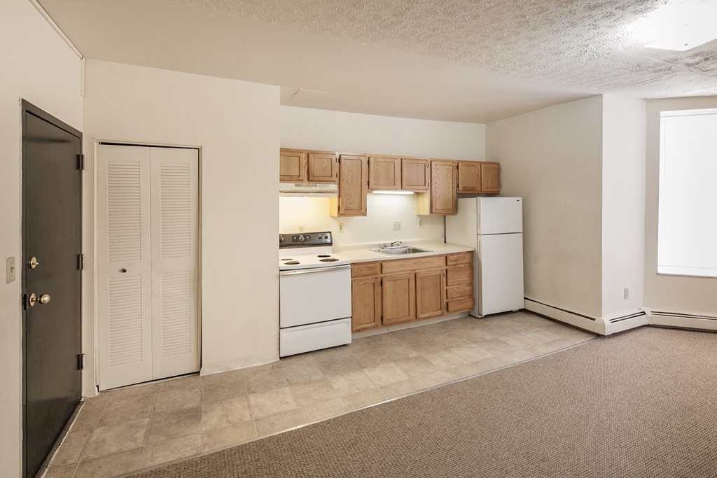 an empty kitchen with white appliances and wooden cabinets