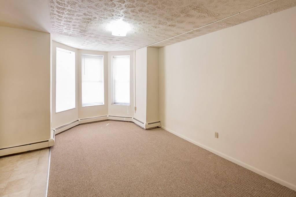 the living room of an empty house with carpet and windows
