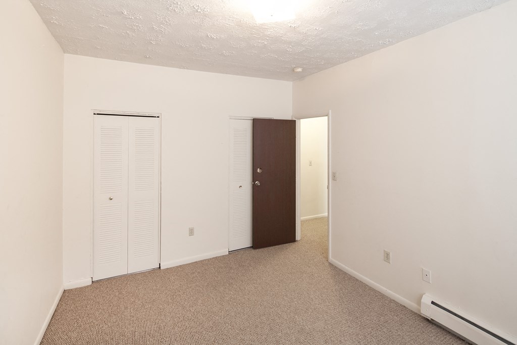 a bedroom with white walls and a closet and a door