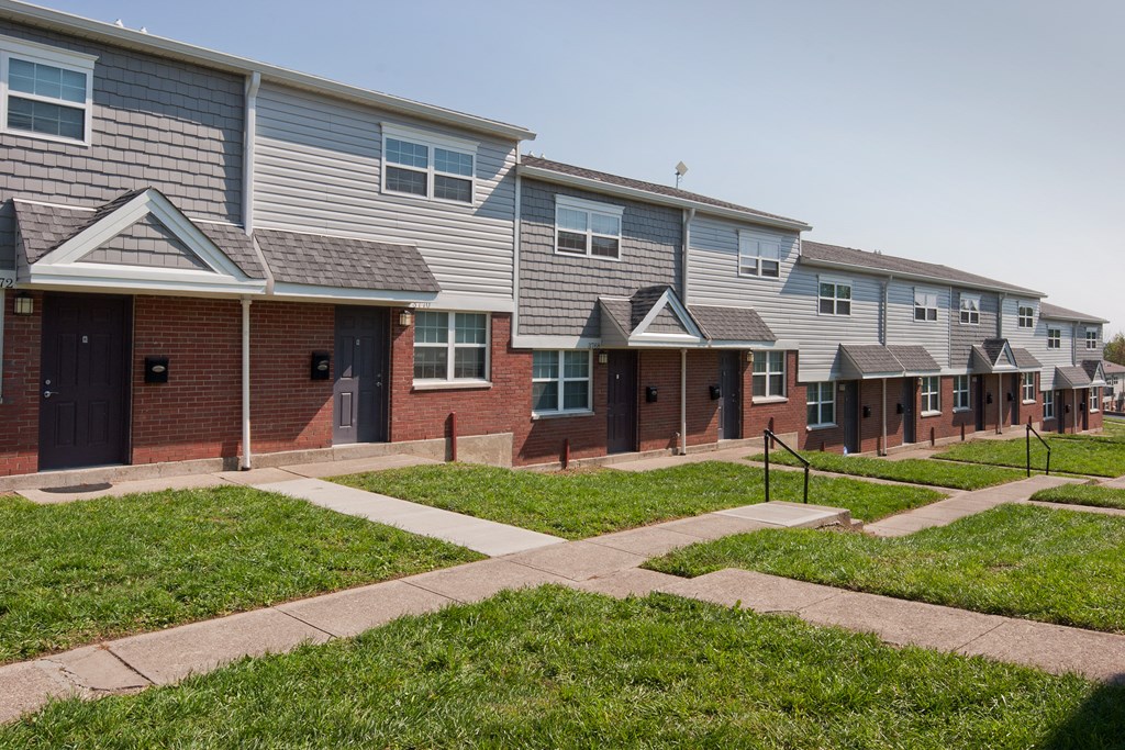 a row of houses with sidewalk and grass