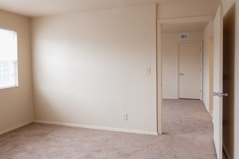 a room with a carpeted hallway and a door to a bedroom