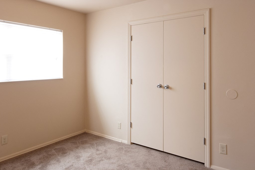a bedroom with two closet doors and a window
