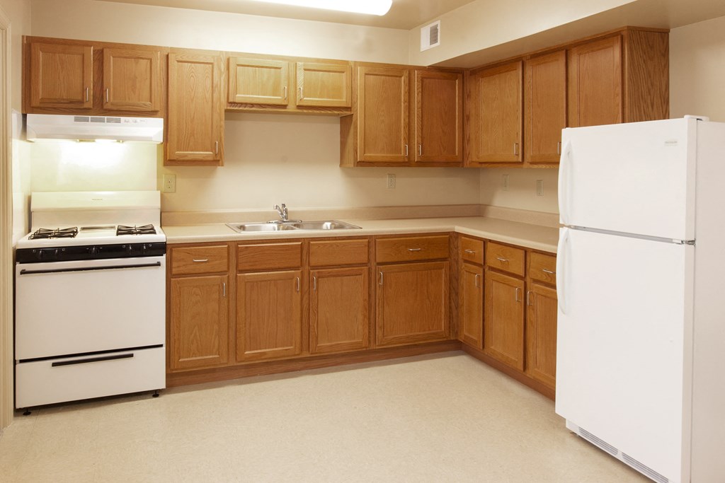 an empty kitchen with white appliances and wooden cabinets