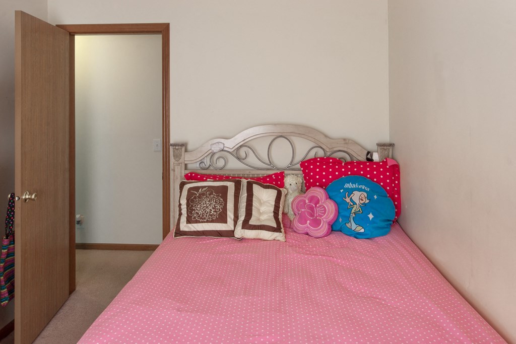 a bedroom with a pink bed and pillows and a closet