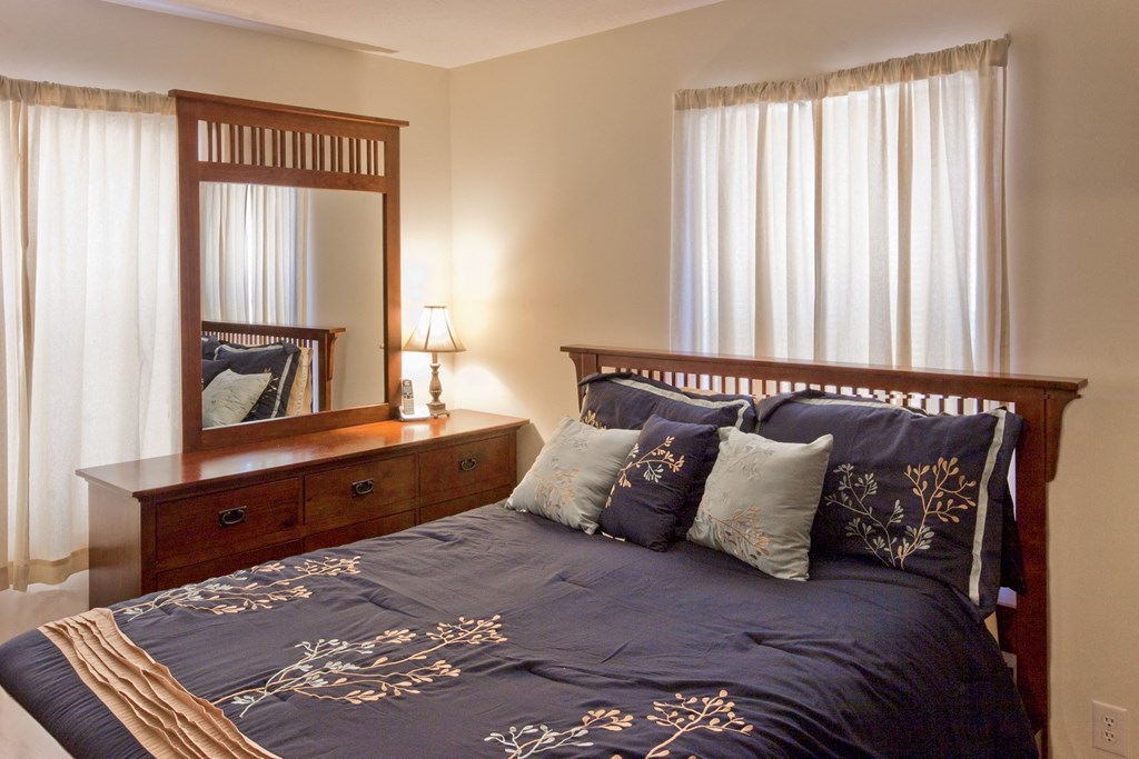 a bedroom with a bed and a dresser with a mirror