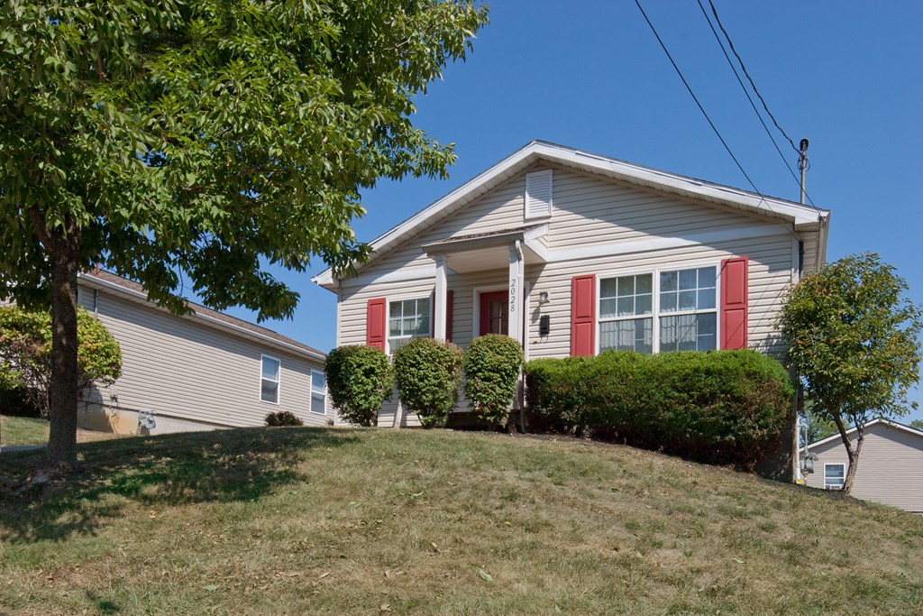 a white house with red shutters on the side of a hill