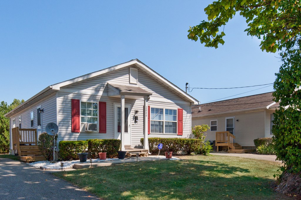 the front of a white house with red shutters and a lawn