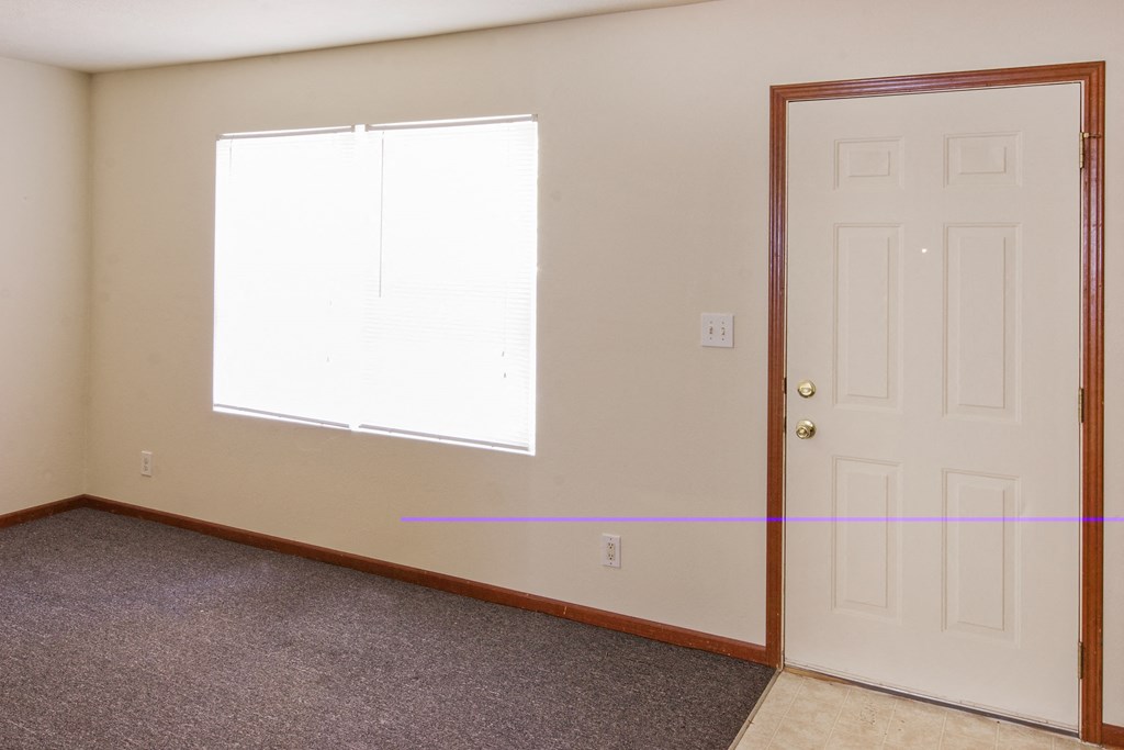 an empty living room with a white door and a window