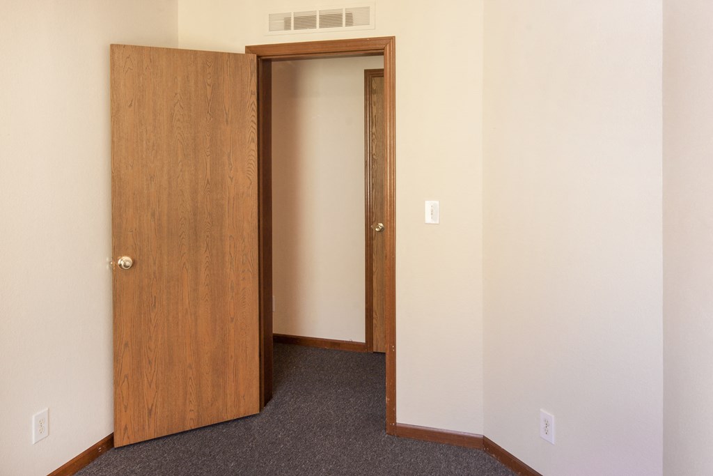 an empty room with a door open and a closet