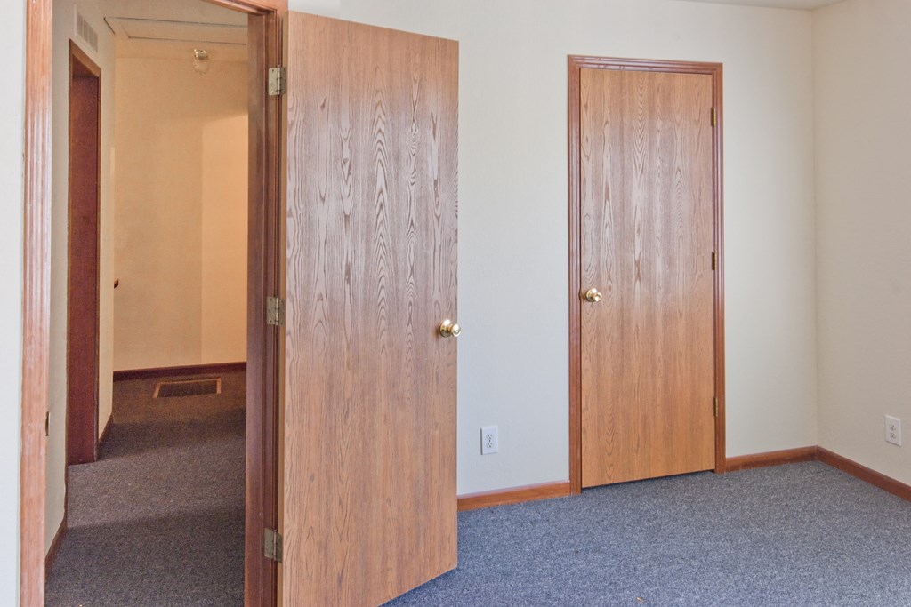 an empty room with two doors and a carpeted floor