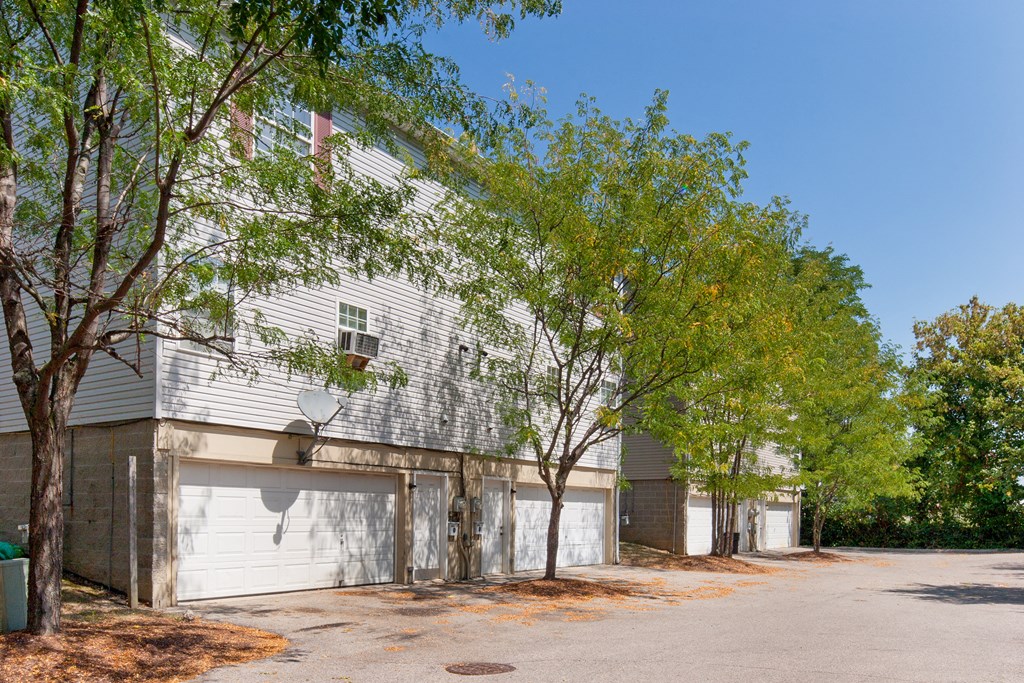 a white building with white garage doors and trees