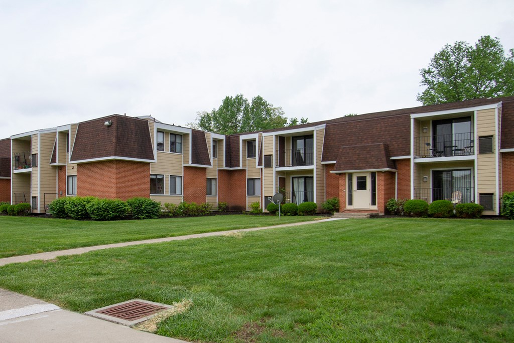 an apartment building with a green lawn and a sidewalk