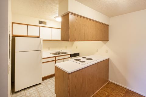a kitchen with white appliances and wooden cabinets and a white refrigerator
