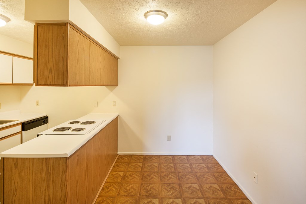 the view of a kitchen with a stove and counter top in an empty apartment