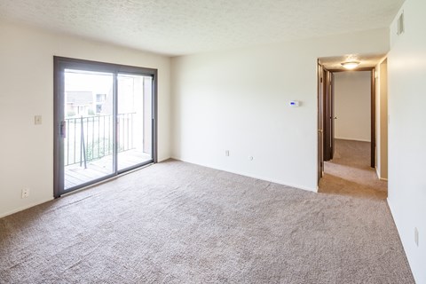 an empty living room with a sliding glass door to a balcony