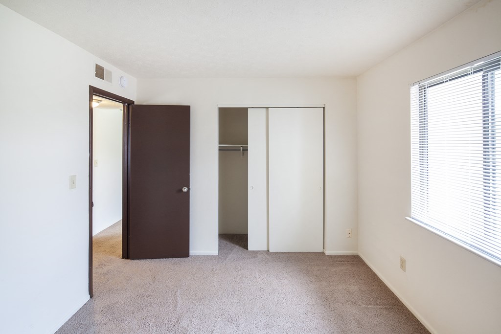 an empty bedroom with a closet and a window