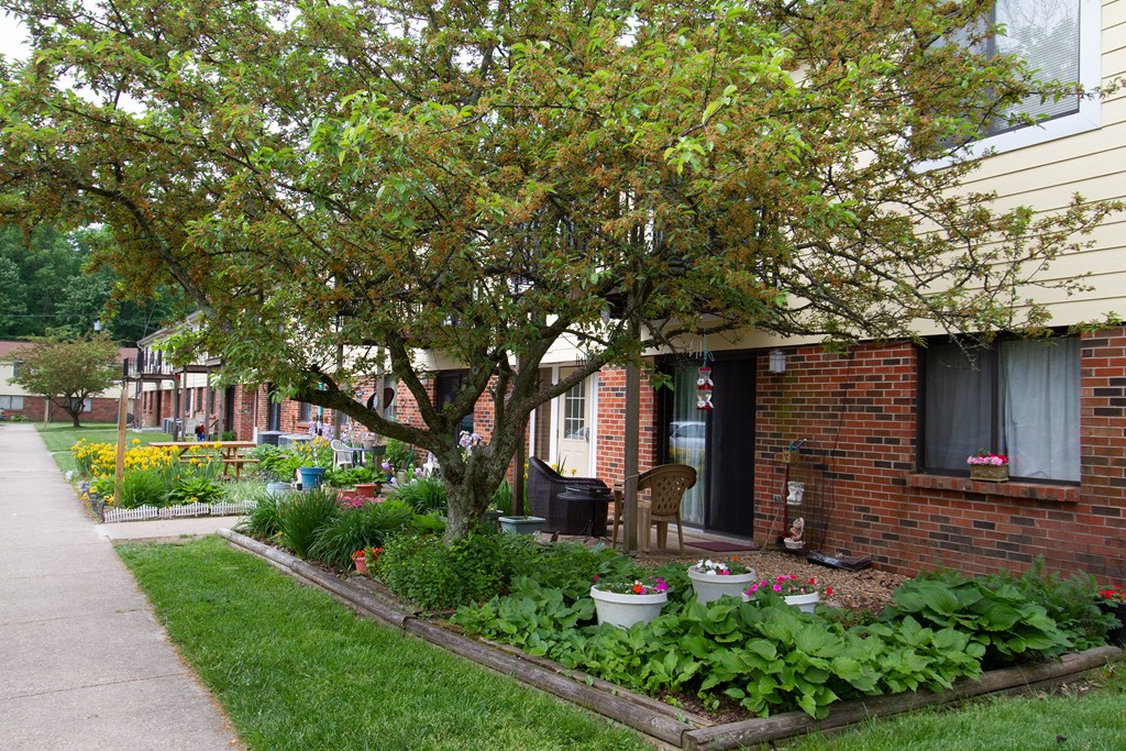 a garden in the front yard of a brick house