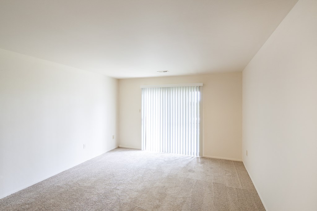 a room with white walls and a window with white blinds