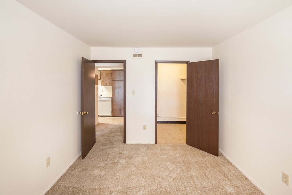 a bedroom with two doors and a carpeted floor