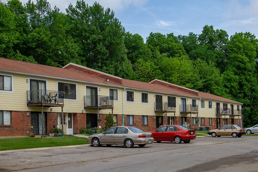 a row of apartment buildings with cars parked in front