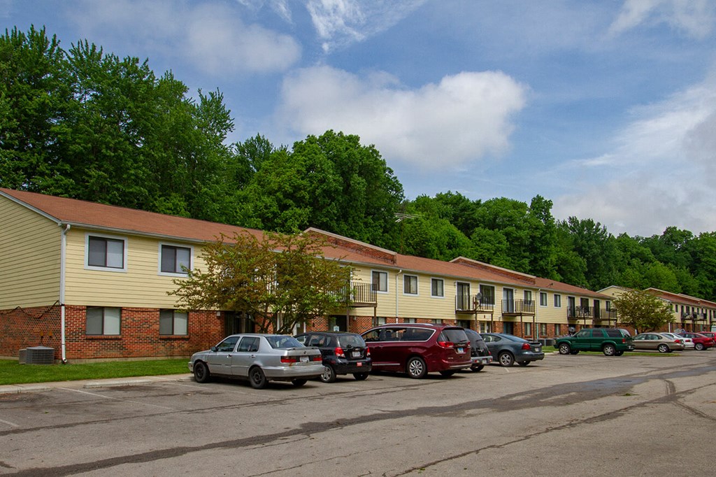 a row of apartment buildings with cars parked in a parking lot