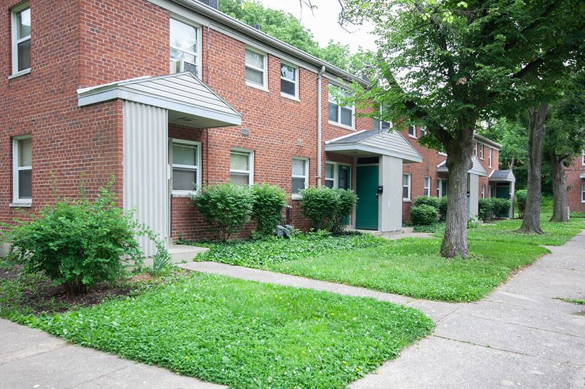 a sidewalk in front of a brick apartment building