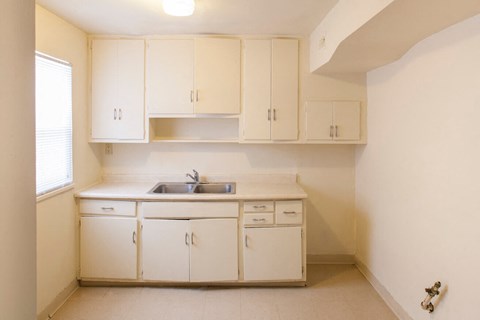 an empty kitchen with white cabinets and a sink