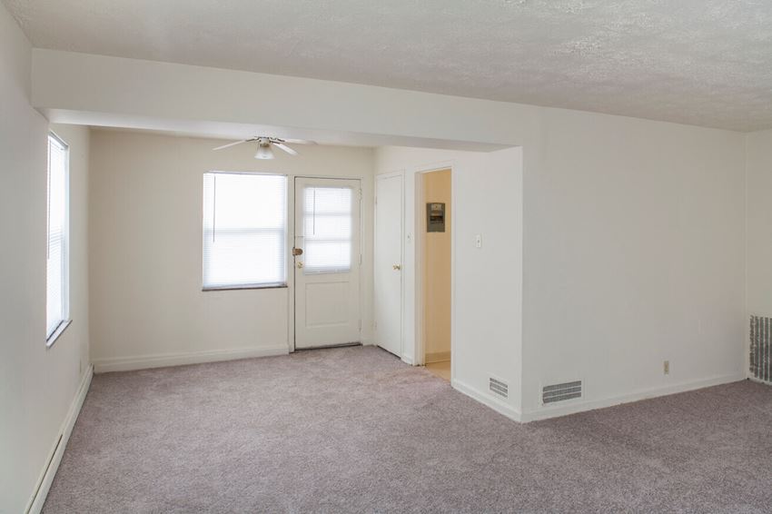 an empty living room with a white door and a ceiling fan