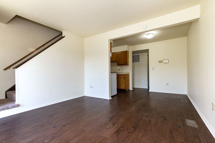 an empty living room with wood flooring and white walls