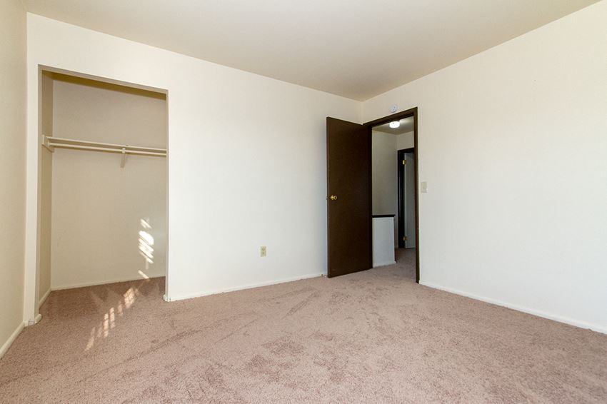 an empty bedroom with a closet and a door to a hallway