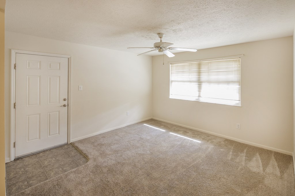 an empty living room with a ceiling fan and a window