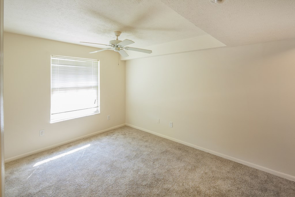 an empty room with a ceiling fan and a window