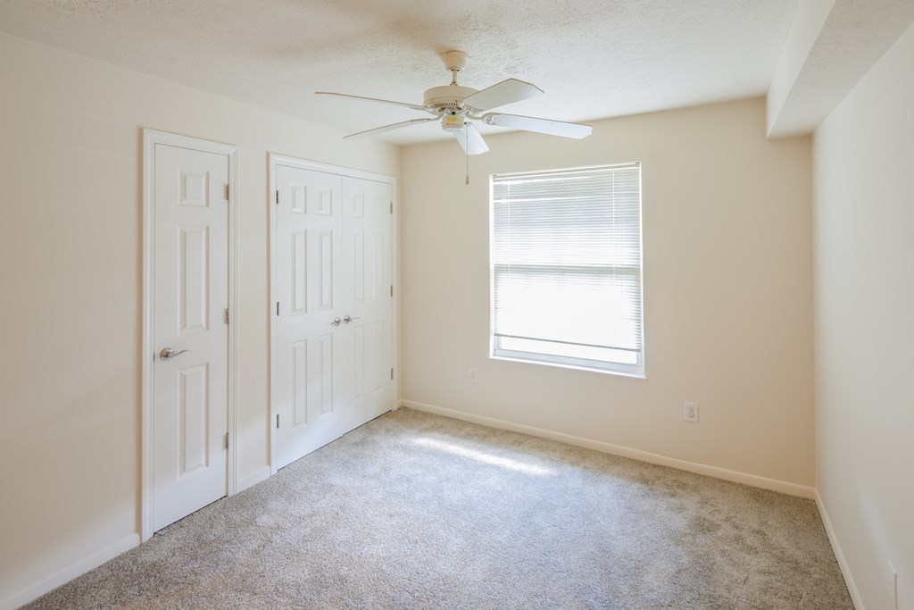 an empty room with a ceiling fan and a closet