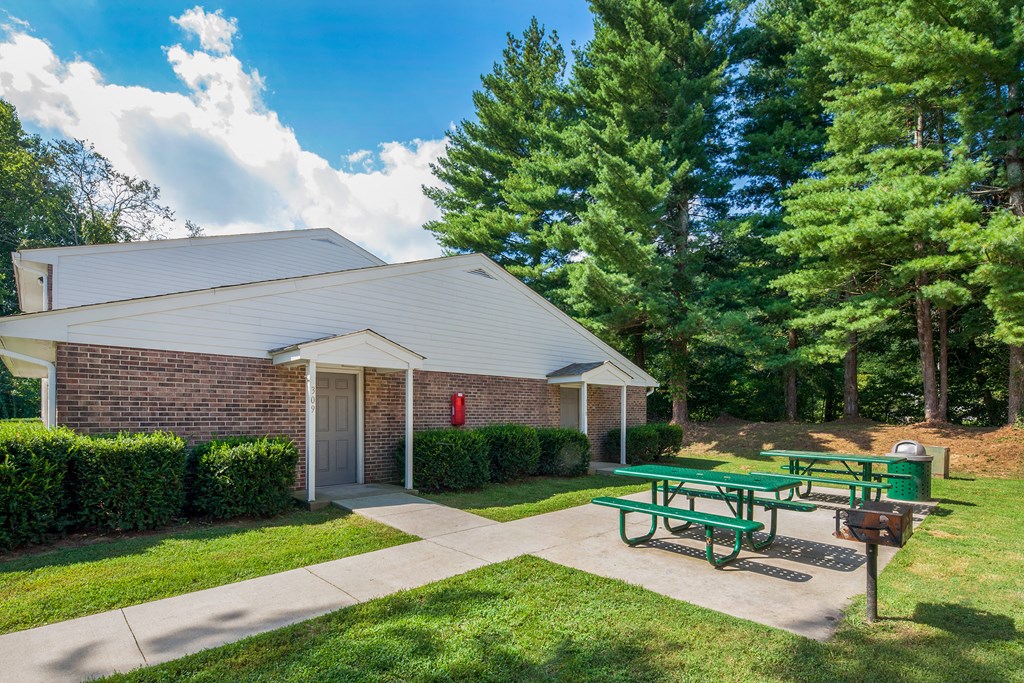a picnic area in front of a brick building with picnic tables