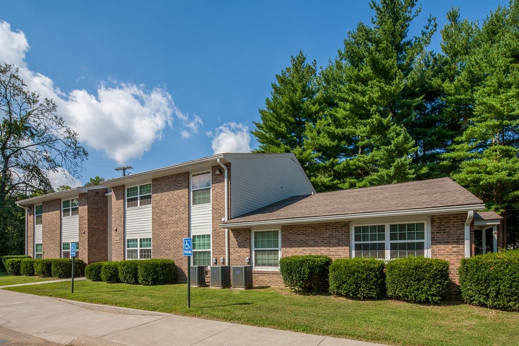 an apartment building with a brick exterior and green grass and trees