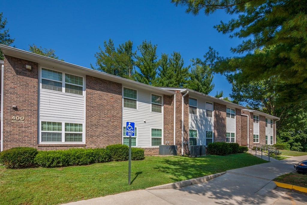 a brick apartment building with a sidewalk and grass