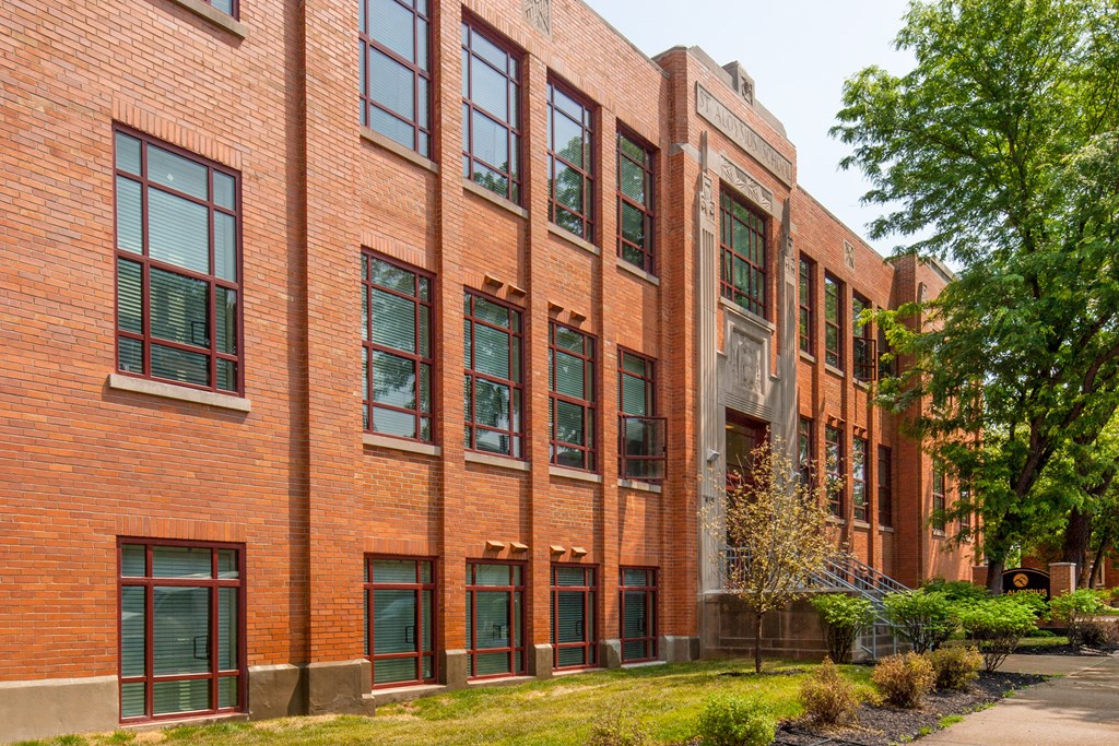 a large brick building with green windows and a sidewalk